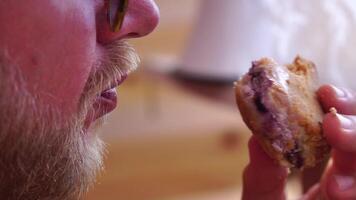 Mens aan het eten kaastaart. gebaard Mens in zonnebrillen aan het eten kwarktaart Aan de strand. gelukkig Mens is glimlachen en resting Bij zee. gebaard vent genieten van maaltijden Aan zomer vakantie. langzaam beweging. video