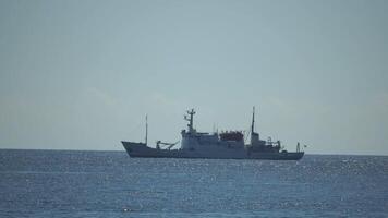 Fishing boat trawler catches fish while sailing on sea. A commercial fishing boat on the horizon in a distance sail to catch school of fish on calm sea surface in summer. Commercial catch of sea fish. video