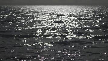 abstract zee zomer oceaan zonsondergang natuur achtergrond. klein golven Aan gouden water oppervlakte in beweging vervagen met gouden bokeh lichten van zon. vakantie, vakantie en recreatie. weer en klimaat verandering video