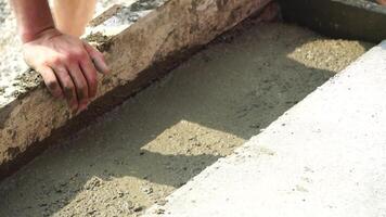 Construction, Worker Hands smooth wet cement in wooden frame at a construction site during daytime to ensure an even surface video