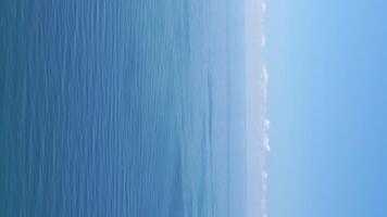 Vertical aerial view on sea water surface, camera flies over clear sea water. Sun glare. Abstract nautical summer ocean nature. Holiday, vacation and travel concept. Nobody. Vertical video