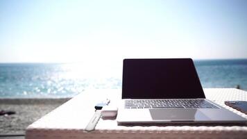 moderno taccuino e smartphone a mare oceano spiaggia bar piace Perfetto posto di lavoro per distanza libero professionista. il computer portatile computer con finto su vuoto schermo per pubblicizzare contenuto. lento movimento. video