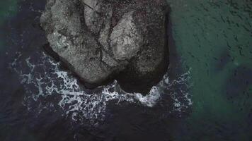 Aerial sea wave rocks. Top down aerial view crashing waves flowing on seashore volcanic basalt rocks in a dark sea, ocean sea surface. Amazing sea waves crashing on rocks seascape. video
