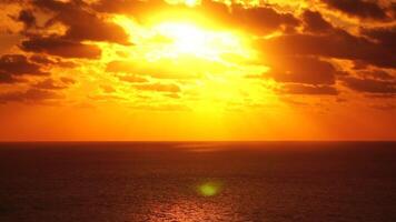 een rood brandend zonsondergang over- zee. abstract natuur zomer oceaan zee achtergrond. klein golven Aan gouden warm water oppervlakte met bokeh lichten van zon. weer en klimaat verandering video