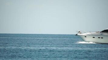 yacht su calma mare. lusso crociera viaggio. lato Visualizza di bianca barca su in profondità blu acqua. vicino su Visualizza di ricco yacht andare in barca mare. estate viaggio su lusso nave. lento movimento video