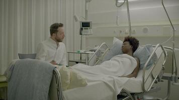 Young African Woman With Curly Hair Lying in Clinic Bed Talking to Physician video