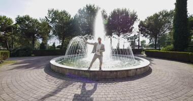 Lycklig ung man dans i vatten fontän i sommar tid video