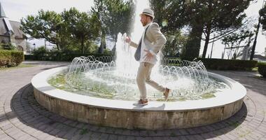 gelukkig jong Mens dansen in water fontein in zomer tijd video