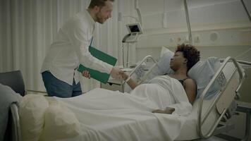 Young African Woman With Curly Hair Lying in Clinic Bed Talking to Physician video