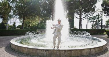 gelukkig jong Mens dansen in water fontein in zomer tijd video