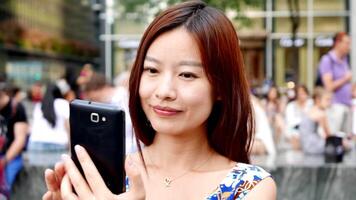 Jeune asiatique femme en utilisant intelligent téléphone dispositif dans le ville des rues video