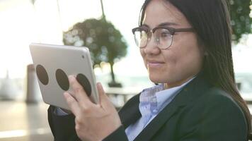 Jeune asiatique femme d'affaires avec des lunettes en utilisant numérique tablette écran video