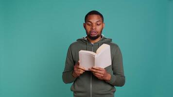 Man reading book aloud, narrating story for audience. Person enjoying literature novel, reciting from pages, entertaining spectators, isolated over studio background, camera B video