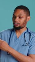 Vertical Male nurse holding handheld nebulizer used for delivering aerosols based medicines, helping control respiratory symptoms. Healthcare specialist presents breathing device, studio background, camera A video