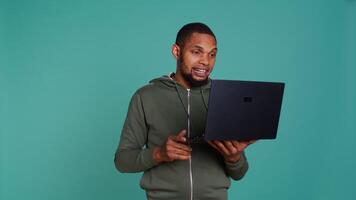 alegre homem tendo divertido conversação com amigos durante teleconferência encontro usando computador portátil, estúdio fundo. feliz pessoa tendo Diversão interagindo com companheiros durante conectados Video chamada, Câmera b