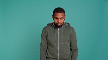 Portrait of cheerful african american man smiling, waving hand, isolated over studio background. Happy expressive person saluting person off camera, being friendly, camera B video