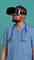 Vertical Nurse wearing virtual reality headset remotely operating patient. Healthcare specialist using high tech futuristic modern medical vr gadget, isolated over blue studio background, camera B video