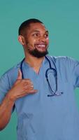 Vertical Male nurse using mobile phone to take selfies during hospital job shift break. Healthcare worker using smartphone to take pictures of himself, isolated over studio background, camera B video