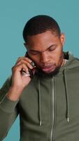 Vertical Irked african american man fighting with friends during telephone call, isolated over studio background. Outraged person arguing with mates during conversation on mobile phone, camera A video