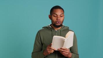Man reading book aloud, narrating story for audience. Person enjoying literature novel, reciting from pages, entertaining spectators, isolated over studio background, camera A video