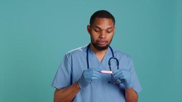 Portrait of doctor holding pregnancy test, doing instructional for parents awaiting kids, studio background. Healthcare professional doing tutorial on how to read pregnancy kit result, camera A video