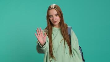 Assertive young woman doing stop hand gesture and talking. Annoyed girl doing firm halt sign gesturing, wishing to end concept, isolated over blue studio background, camera A video