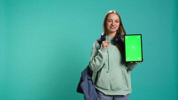 Portrait of woman presenting tablet with chroma key display, isolated over studio background. Young girl creating promotion with blank copy space mockup digital device, camera B video