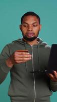 Vertical Happy man adding payment method on website using laptop, delighted to take advantage of promotions, studio background. Person thrilled to do internet shopping, typing credit card data, camera B video