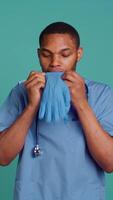 Vertical Male nurse putting on rubber gloves, preparing for surgery, isolated over studio background. Practitioner wearing sterile surgical equipment before medical exam, camera B video