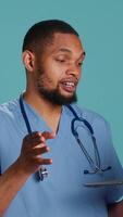 Vertical Friendly upbeat medic doctor in videocall meeting using laptop, providing treatment plan. Jolly hospital staff member listening to patient health problems in online telemedicine call, camera A video