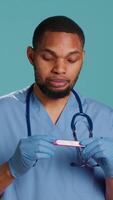 Vertical Portrait of doctor holding pregnancy test, doing instructional for parents awaiting kids, studio background. Healthcare professional doing tutorial on how to read pregnancy kit result, camera A video