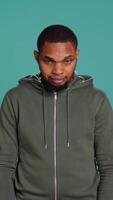 Vertical Portrait of cheerful african american man smiling, waving hand, isolated over studio background. Happy expressive person saluting person off camera, being friendly, camera B video