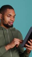 Vertical Upbeat man adding payment method on online website using tablet. Person thrilled to do internet shopping using device, typing debit card data, isolated over studio background, camera A video