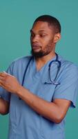 Vertical Male nurse holding handheld nebulizer used for delivering aerosols based medicines, helping control respiratory symptoms. Healthcare specialist presents breathing device, studio background, camera B video