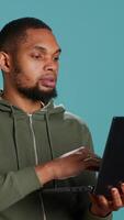 vertical feliz homem adicionando Forma de pagamento método em local na rede Internet usando computador portátil, Deleitado para levar vantagem do promoções, estúdio fundo. pessoa emocionados para Faz Internet compras, digitando crédito cartão dados, Câmera uma video