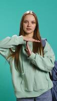 Vertical Portrait of assertive woman asking for timeout, doing hand gestures, feeling fatigued. Unhappy girl doing vehement pause sign gesturing, wishing for break, studio background, camera B video