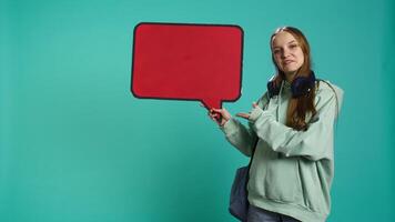 sonriente mujer participación rojo habla burbuja firmar de vacío Copiar espacio para mensaje. jubiloso adolescente presentación pensamiento burbuja cartulina usado como promoción concepto, aislado terminado estudio fondo, cámara si video