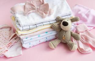 Baby crocketed toy of dog next to a stack rompers for kids photo
