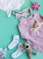 Set of pink clothes and accessories for newborn baby. Knitted toys rabbit and dog, romper, socks and handband photo