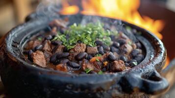 The intense aroma of slowcooked pork and black beans fill the air as a traditional Brazilian Feijoada simmers over an open flame. The deep earthy flavors of this dish combin photo