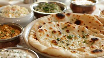 Plates of fluffy goldenbrown flatbread known as naan are p alongside bowls of creamy hummus and tangy tzatziki for dipping photo