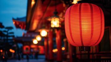 The intense glare of a bright redgold lantern hanging outside a traditional Japanese temple illuminated against the dark night sky during Golden Week festivities photo