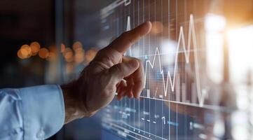 A man is pointing at a graph on a transparent screen showing market and economy trends photo