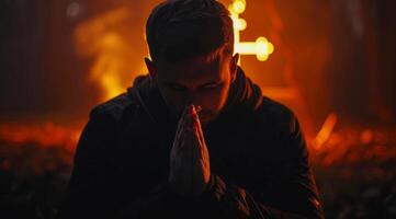 Devout faithful christian prays in front of the cross that is burning photo