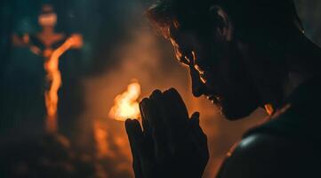 Devout faithful christian prays in front of the cross that is burning photo
