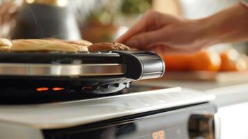 Detail shot of the adjustable temperature on a sandwich maker with a hand turning it to adjust the heat for cooking photo