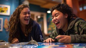 Two friends laugh as they compete against each other in a quiz game testing their knowledge of different species of fish and other sea creatures photo