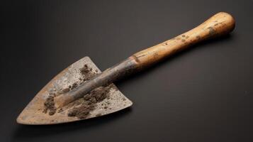 A weathered wooden handle on a spade its edge shard to a fine point and caked with layers of dark rich soil photo