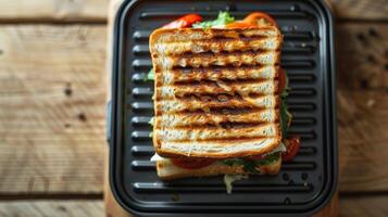A topdown view of a sandwich maker with a perfectly pressed sandwich visible through the viewing window photo