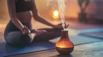An essential oil diffuser is p next to a persons yoga mat emphasizing the use of aromatherapy in enhancing the healing properties of a yoga practice photo